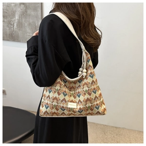 Detail of geometric jacquard shoulder bag featuring fashion patch and bead tassel