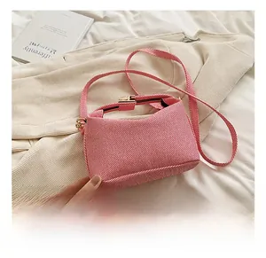 Detail of pink and white striped crossbody bag with gold buckle on a soft fabric background