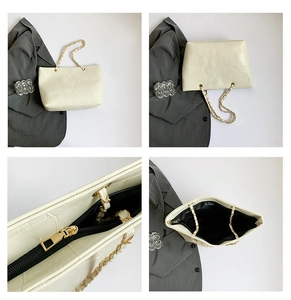 Detail view of large beige tote bag featuring crocodile pattern leather and gold metal chain
