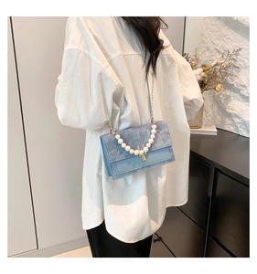Détail du sac tissé bleu clair avec grande poignée en perles et chaîne dorée