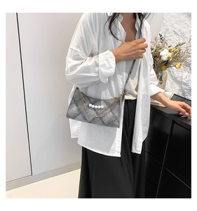 Dettaglio borsa trapuntata denim grigio con perle eleganti e catena in metallo oro