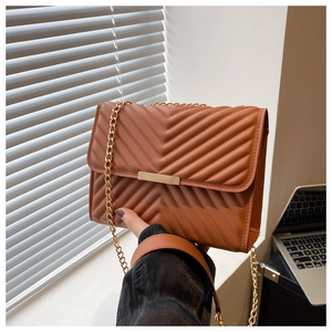 Detail of caramel brown quilted leather shoulder bag with gold chain and metal buckle
