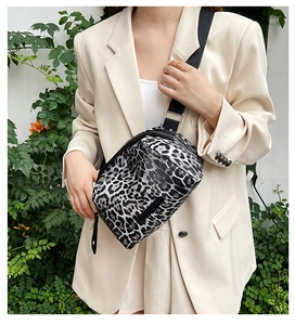 Close-up of leopard print crossbody bag with black nylon strap and silver metal hardware