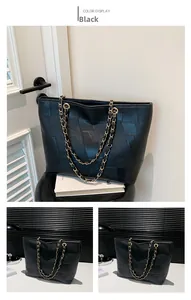 Detail of black leather tote bag featuring irregular geometric texture and gold chain strap