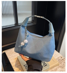 Détail du sac barillet en denim bleu clair avec surpiqûres et breloque en perles