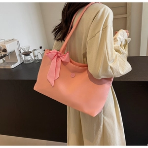 Detailaufnahme der rosa Tragetasche mit Karoschleife an einem Model im Café