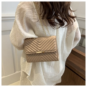Beige quilted shoulder bag with gold chain strap shown on model for size and fit