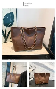 Detail of a brown tote bag with patchwork texture and gold-tone chain strap
