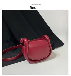 Detail view of red saddle shoulder bag with tubular thickened edges on black blazer
