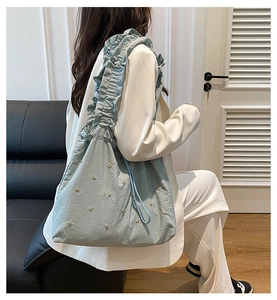 Detail van lichtblauwe shopper met ruches aan schouderband en metalen bloemnagels