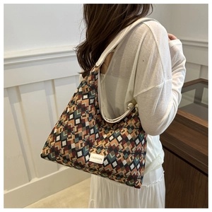 Detail of a large geometric pattern tote bag with white leather strap on female model