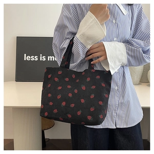 Détail d'un grand sac cabas en velours côtelé noir avec imprimé fraises et anses solides