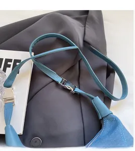 Détail de la bandoulière réglable en denim bleu avec boucle en métal argenté du sac