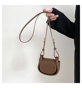 Detail view of a vintage dark brown saddle crossbody bag in matte faux leather texture