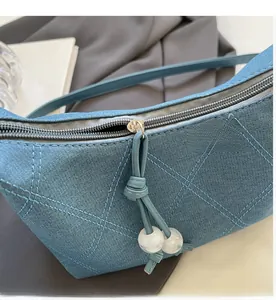 Vue détaillée du sac matelassé en denim avec fermeture éclair argentée et perles marbrées