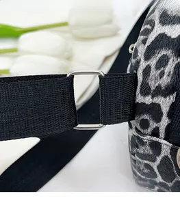 Detail of leopard print bag showing black woven strap and silver metal connection ring