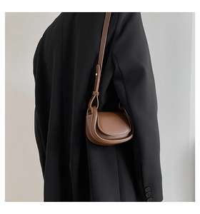 Close-up of a brown leather saddle bag for kids on a model with adjustable strap