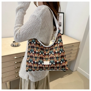 Detail of colorful geometric woven pattern shoulder bag with white leather strap and label