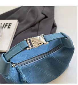 Détail du sac polochon en jean bleu avec matelassage triangulaire et boucle en métal argenté