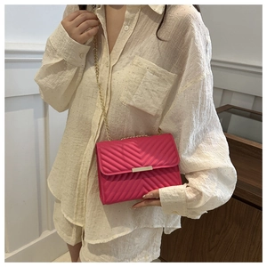 Detail view of pink quilted crossbody bag with golden chain strap and bar closure