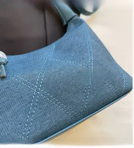 Détail du sac hobo en denim bleu avec surpiqûres matelassées et texture en tissu doux