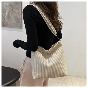 Detail of woven bucket bag with bohemian patterned wide strap shown on a model