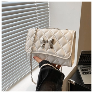 Detail of white quilted chain bag with a silver mirror-finish metallic bow buckle