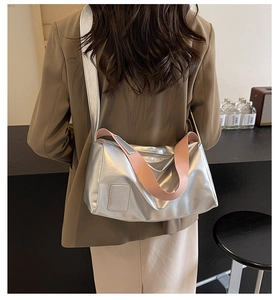Silver metallic crossbody bag with pink straps worn by a model in a trendy urban setting