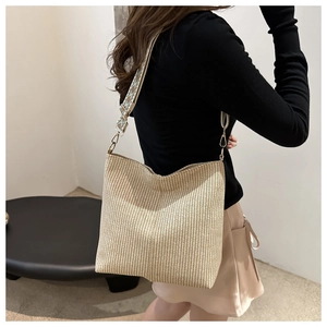 Detail of woven beige bucket bag with decorative jacquard strap on a female model