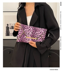 Detailed close-up of a purple leopard print clutch with gold metal trim and magnetic flap