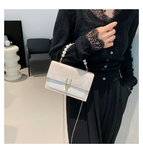 Détail du sac à bandoulière crème avec poignée en perles et fine chaîne dorée
