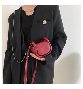 Detail of a dark red mini saddle crossbody bag in high-quality textured leather finish