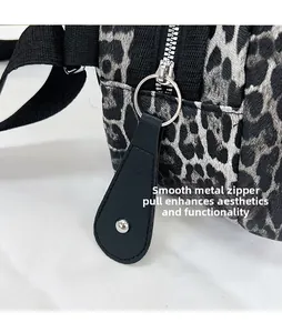 Detail of leopard print shell bag featuring a polished metal zipper and leather puller