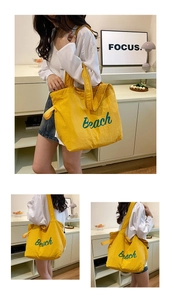 Close-up of lightweight yellow canvas tote bag with green Beach script lettering