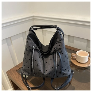 Nahaufnahme der grauen Polka-Dot-Tasche mit schwarzen Schleifen auf einem Holztisch