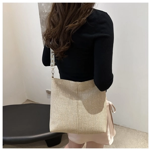 Détail du sac cabas en paille tressée beige avec une large bandoulière ethnique
