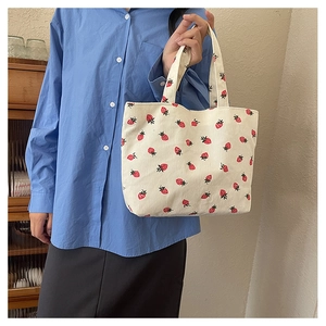 Gros plan sur l'imprimé fraise du sac cabas en velours côtelé beige et sa texture