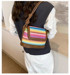 Detail of colorful rainbow woven bag with brown leather base and gold logo lettering