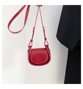 Close-up of minimalist red saddle bag with smooth leather finish and adjustable strap