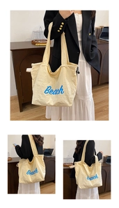 Detail view of cream white nylon tote bag with blue Beach print and drawstring closure