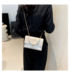 Détail de la poignée en perles et de la texture tisée sur un sac à bandoulière crème