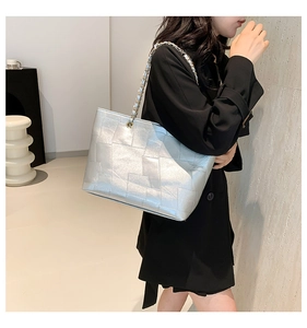 Detail of silver tote bag featuring geometric embossed faux leather and metal chain strap