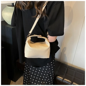 Detail of beige striped woven shoulder bag with adjustable strap and top handle