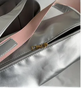Close-up of smooth gold metal zipper on silver metallic crossbody sports bag with pink strap
