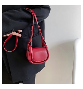 Detail of red mini flap crossbody bag with adjustable gold buckle on black suit background