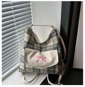 Detail of grey-green plaid tote bag featuring pink bow embroidery and front flap pocket