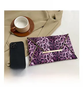 Detail of purple leopard print clutch bag with gold metallic trim on a desk