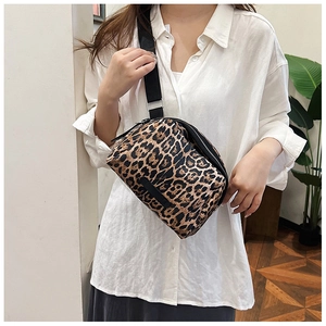 Close-up of leopard print canvas crossbody bag with adjustable wide strap on a model