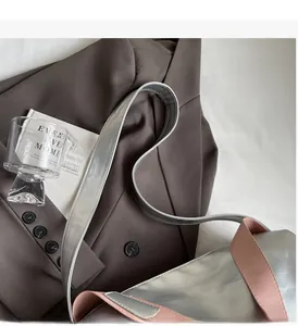 Detail of silver metallic tote bag featuring pink trim handles and wide shoulder strap