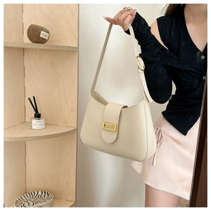 Detail view of cream leather shoulder bag with a textured gold metallic buckle closure